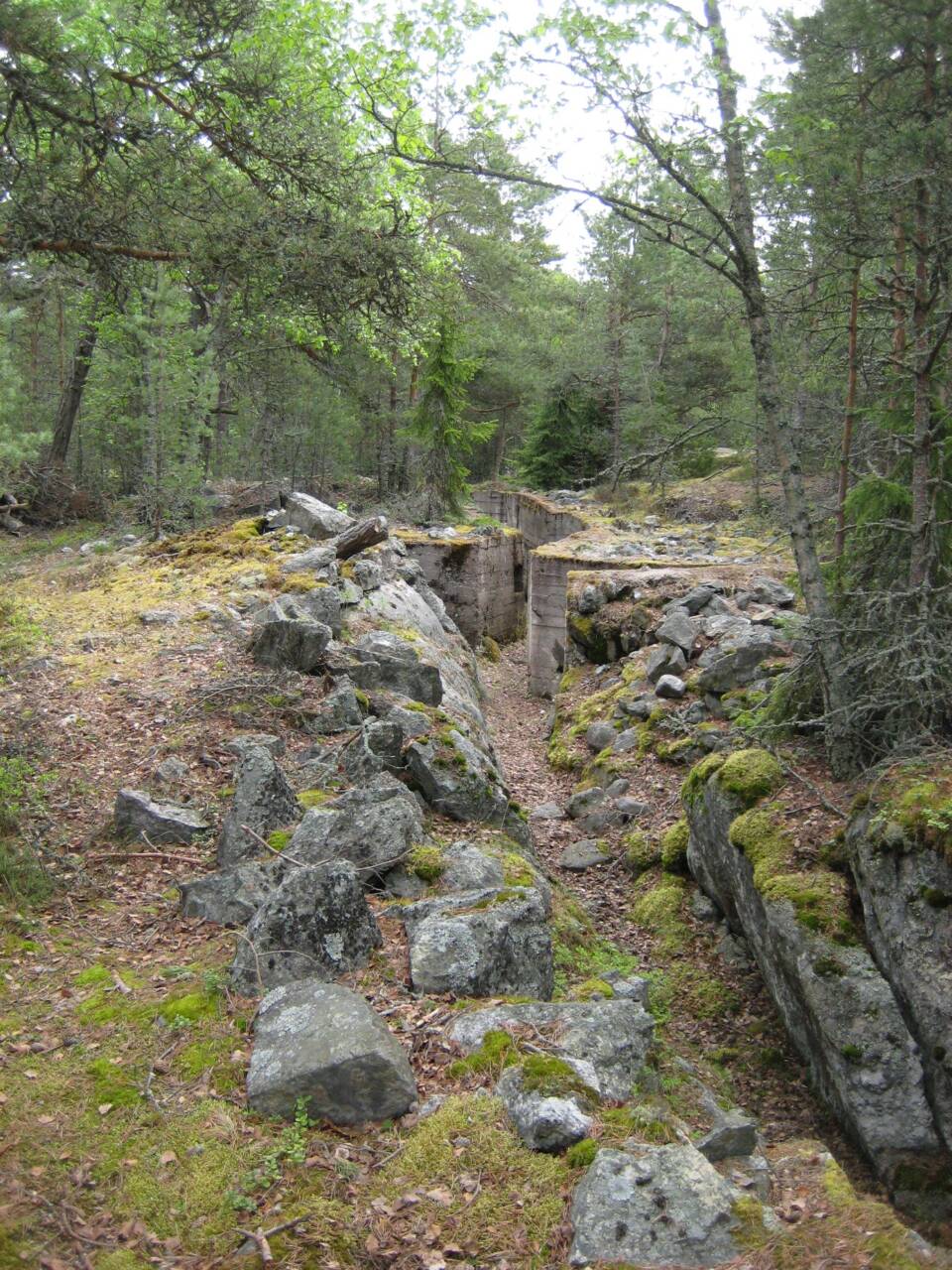 Metsässä kivikkoon rakennettuja ja betonilla lujitettuja juoksuhautamaisia käytäviä.