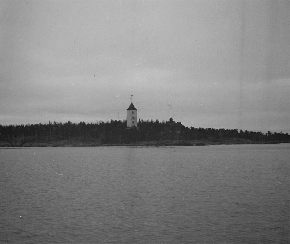 Majakka puustoisella saarella, vanha mustavalkokuva.