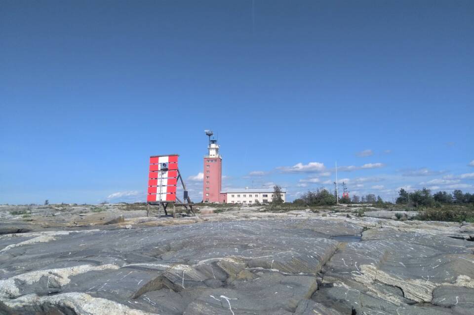 Majakka ja merimerkki kalliolla pilvettömän taivaan alla.