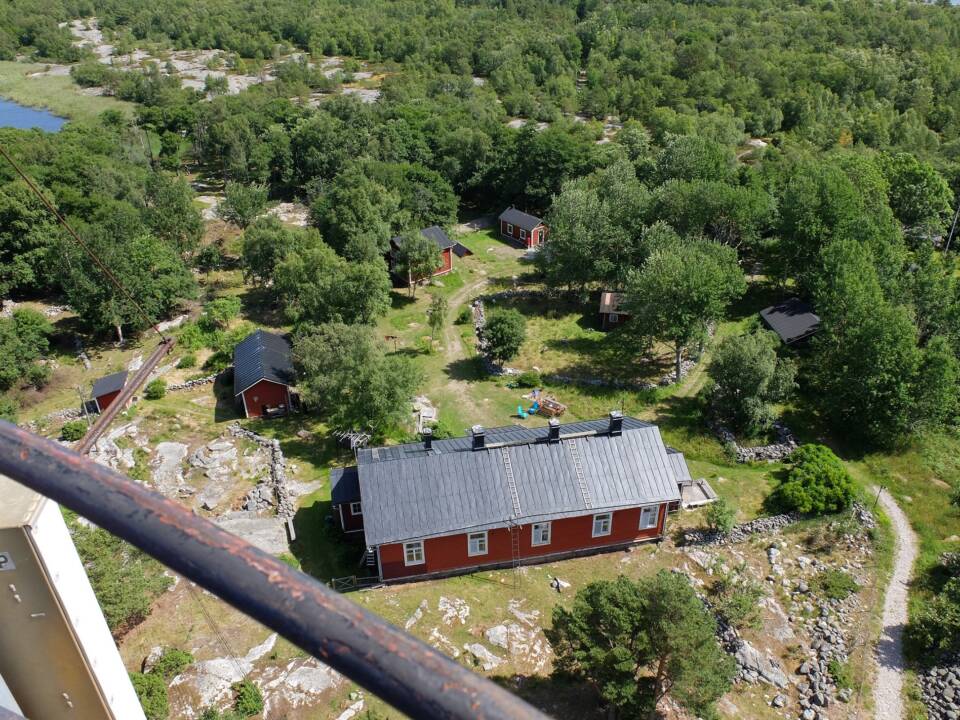 Majakan kaiteen yli katsotanan alhaalla levittäytyviä puita ja paria matalaa puurakennusta.