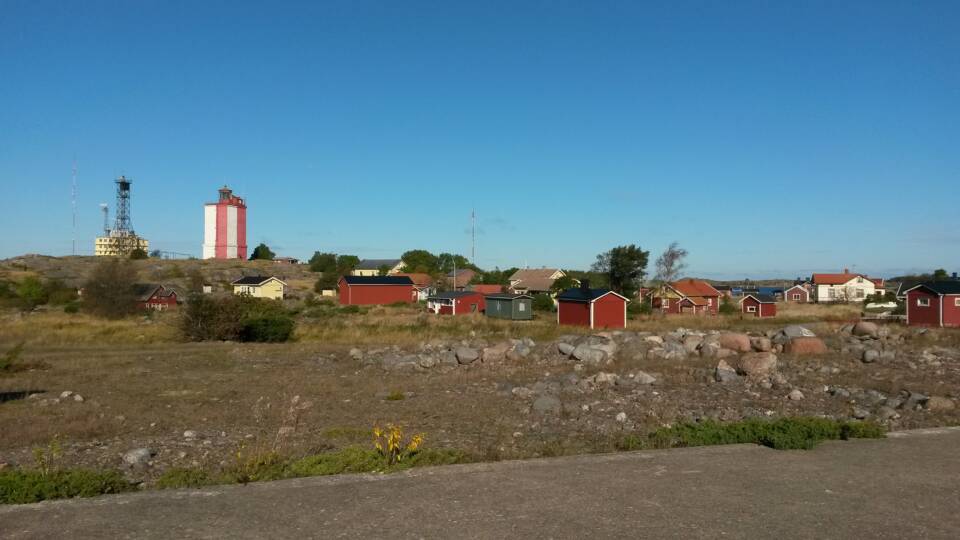 Majakka, torni ja pieniä puisia mökkejä karulla kivikkonummella.