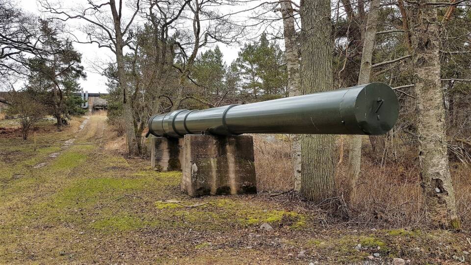 Tolppien varaan nostettu massiivinen metalliputki metsän laidassa.